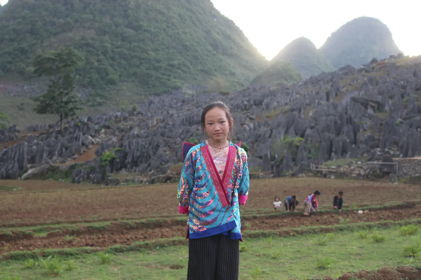 Một em nhỏ trong trang phục truyền thống giữa cao nguyên đá